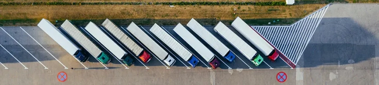 Aerial view of a row of parked delivery trucks at a distribution center.