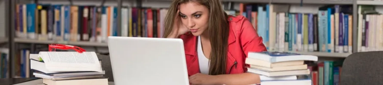 A woman surrounded by books looking at a laptop