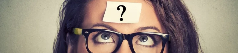 A woman wearing glasses who has a sticky note on her forehead with a question mark written on it