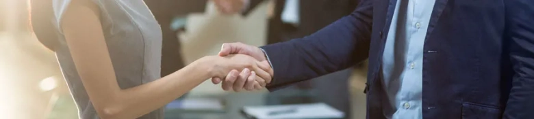 Two suited people shake hands in an office