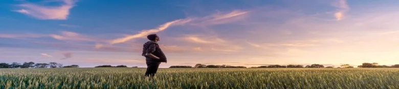 Young person looks into sky in an open field