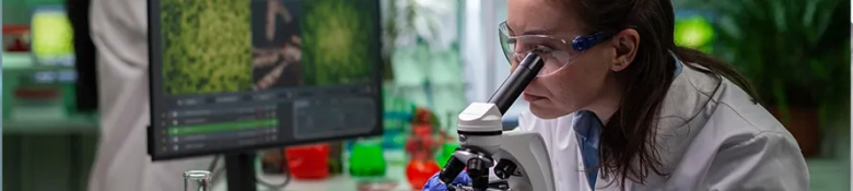 woman in a lab coat looking through a microscope