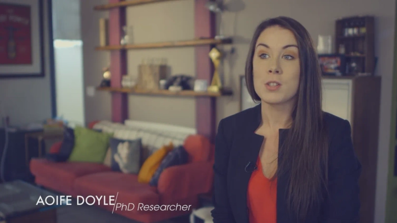 Aoife Doyle, PhD Researcher, speaking in an office environment with a caption displaying her name.