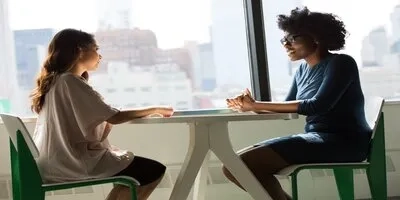 Man and woman sitting across each other at a desk 