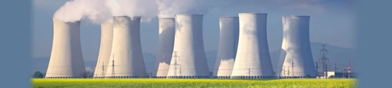 Row of cooling towers at a power plant with steam emissions against a clear sky, symbolizing energy production and environmental impact.