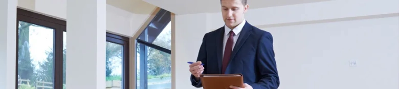 Real estate appraiser in a suit inspecting a property with a digital tablet