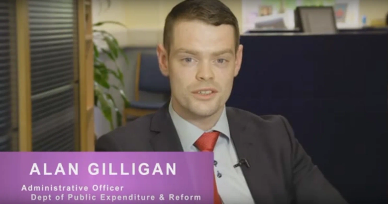 Man in suit with nameplate identifying him as Alan Gilligan, Administrative Officer at the Department of Public Expenditure & Reform.