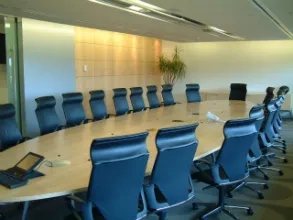 An empty boardroom with chairs surrounding an oval desk