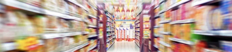 Blurred supermarket aisle representing the fast-paced nature of consumer goods shopping.