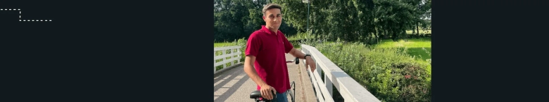 A man in a red polo shirt standing next to his bicycle 