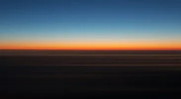 Blurred image of a horizon at sunset with vibrant orange and blue colors.