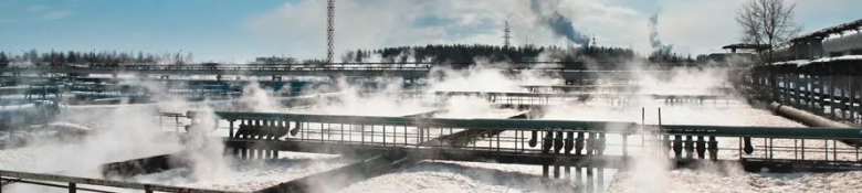 Steam rising from water treatment ponds in a waste management facility during winter.