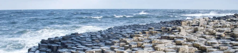 Hexagonal basalt columns of the Giant's Causeway on the coast of Northern Ireland with waves crashing.