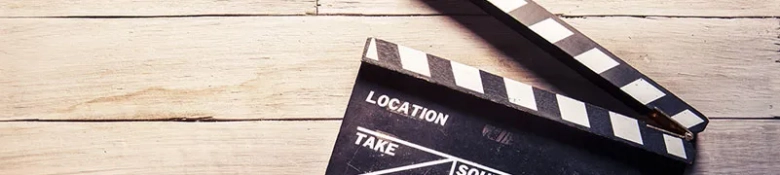 Clapperboard on a wooden surface indicating a film location and take number.