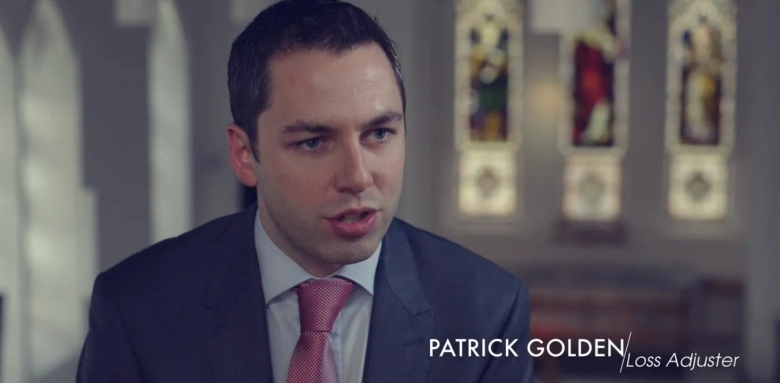 Professional portrait of Patrick Golden, a loss adjuster, with blurred stained glass windows in the background.