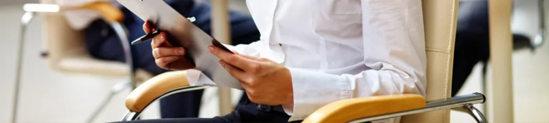 Person sitting in an office chair reviewing documents on a digital tablet.